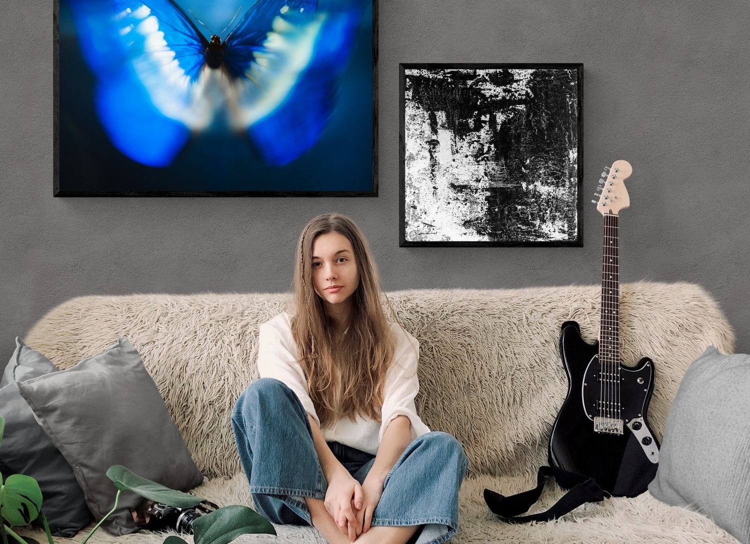 Girl on sofa in a meditative area with a guitar, comfy blanket, and 2 fine art prints framed and on the wall for the home.