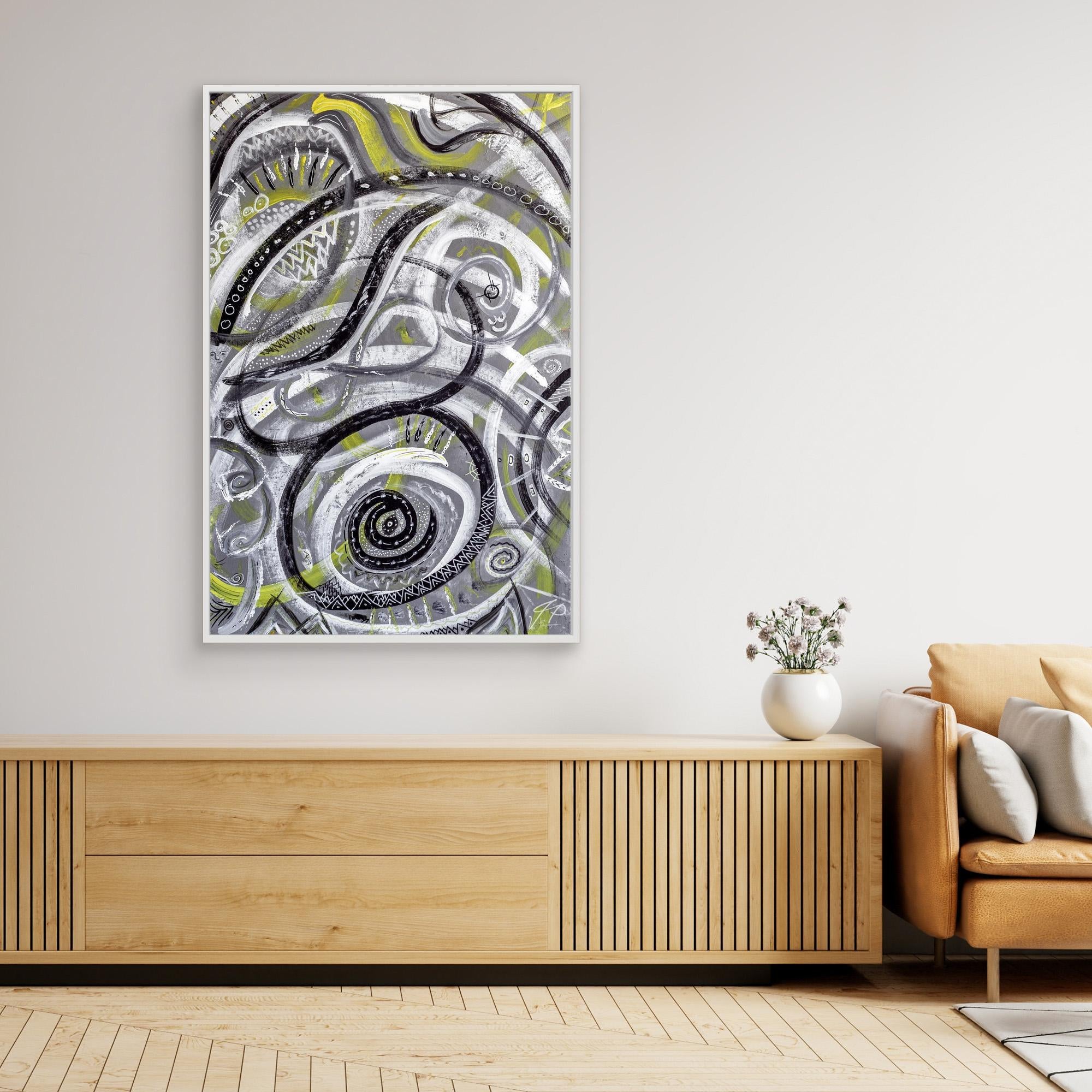 Minimalist living space with abstract black, white, and yellow painting, wood sideboard, tan sofa, and vase of flowers.