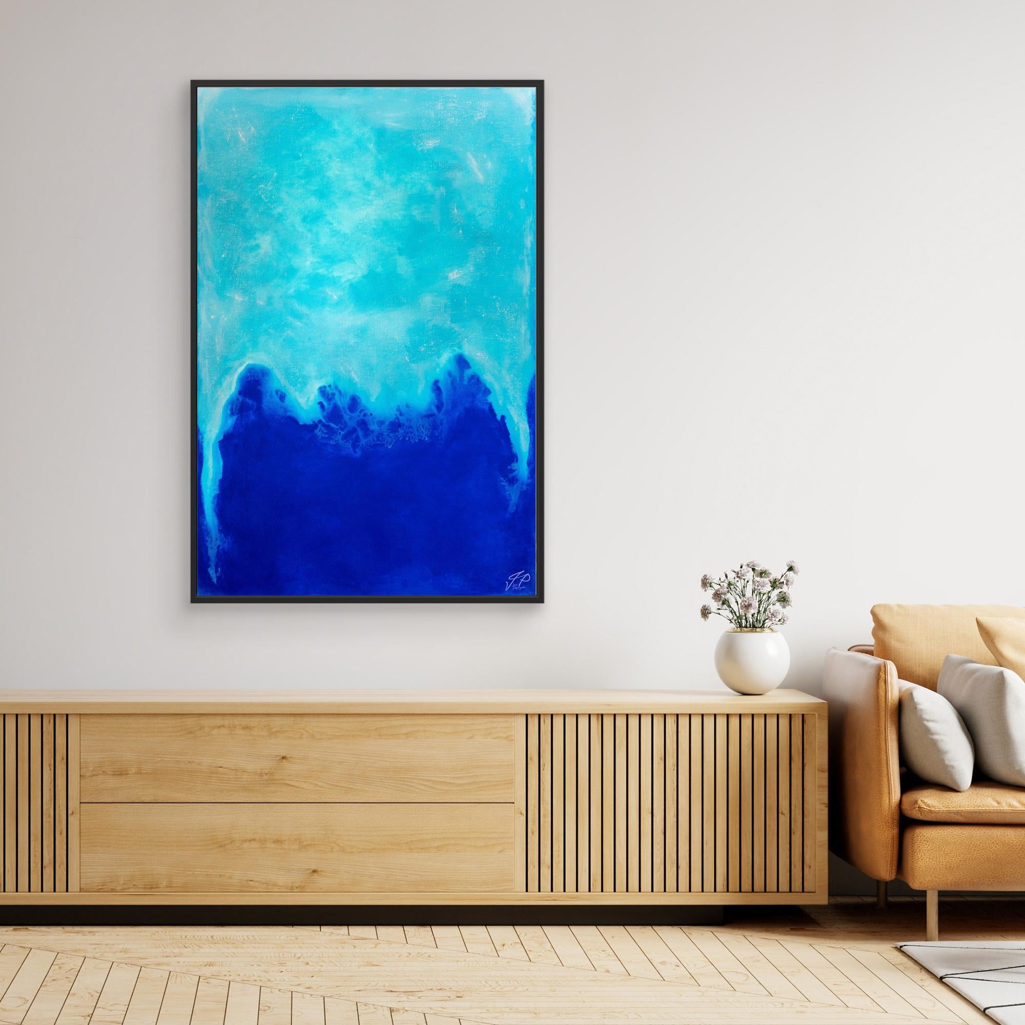 Abstract blue ocean painting above wooden console table, vase with flowers, and beige sofa in room.