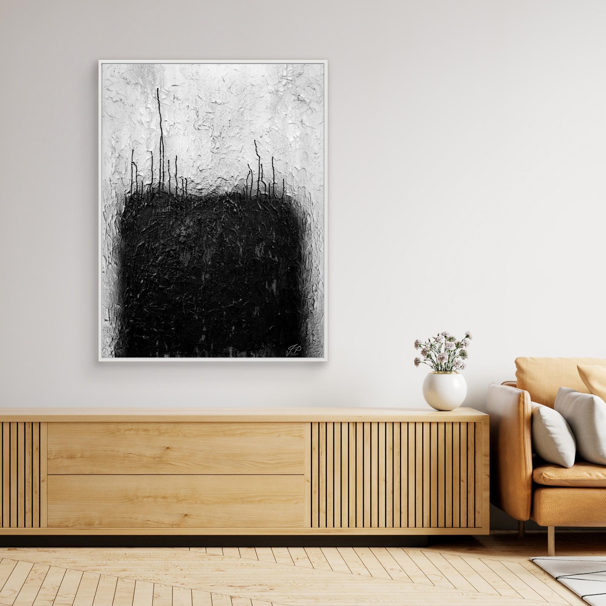 Black and white abstract painting above wooden console table, white vase with flowers, beige sofa.