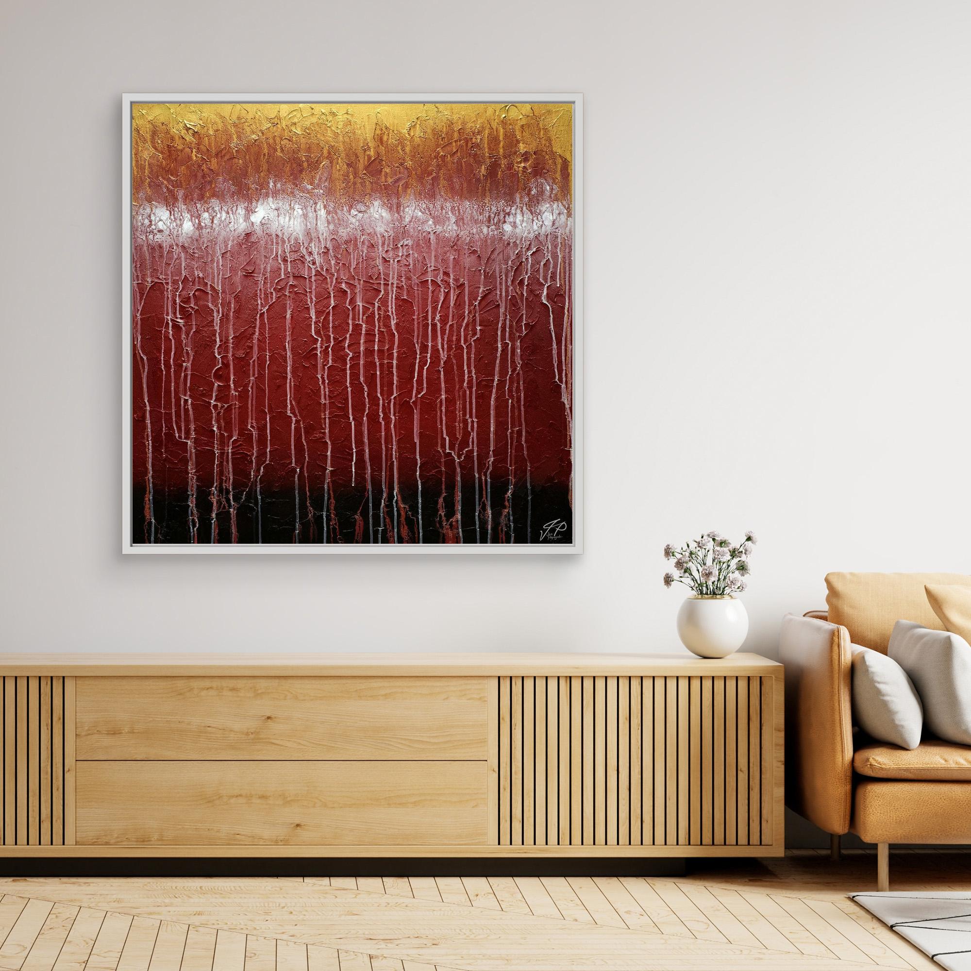 A canvas print of an abstract painting featuring red and white colors, displayed above a wooden cabinet in a room with a beige wall and a yellow armchair.