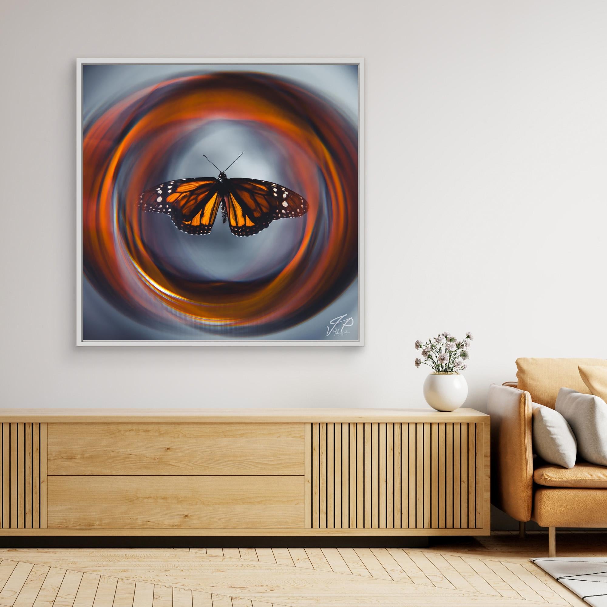 Framed artwork of a monarch butterfly with swirling orange pattern above a wooden console and beige sofa.