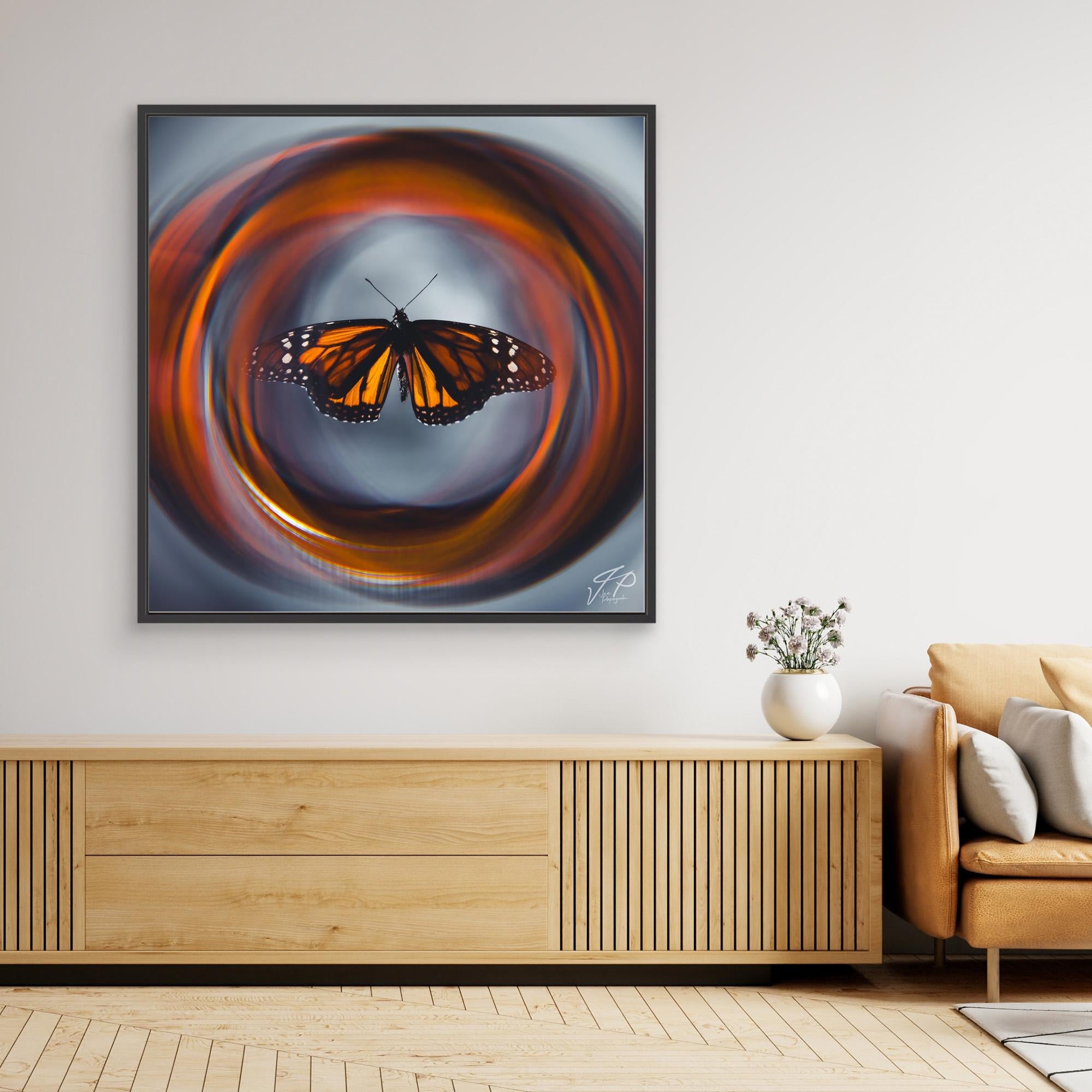 Framed artwork of a monarch butterfly with swirling orange pattern above a wooden console and beige sofa.