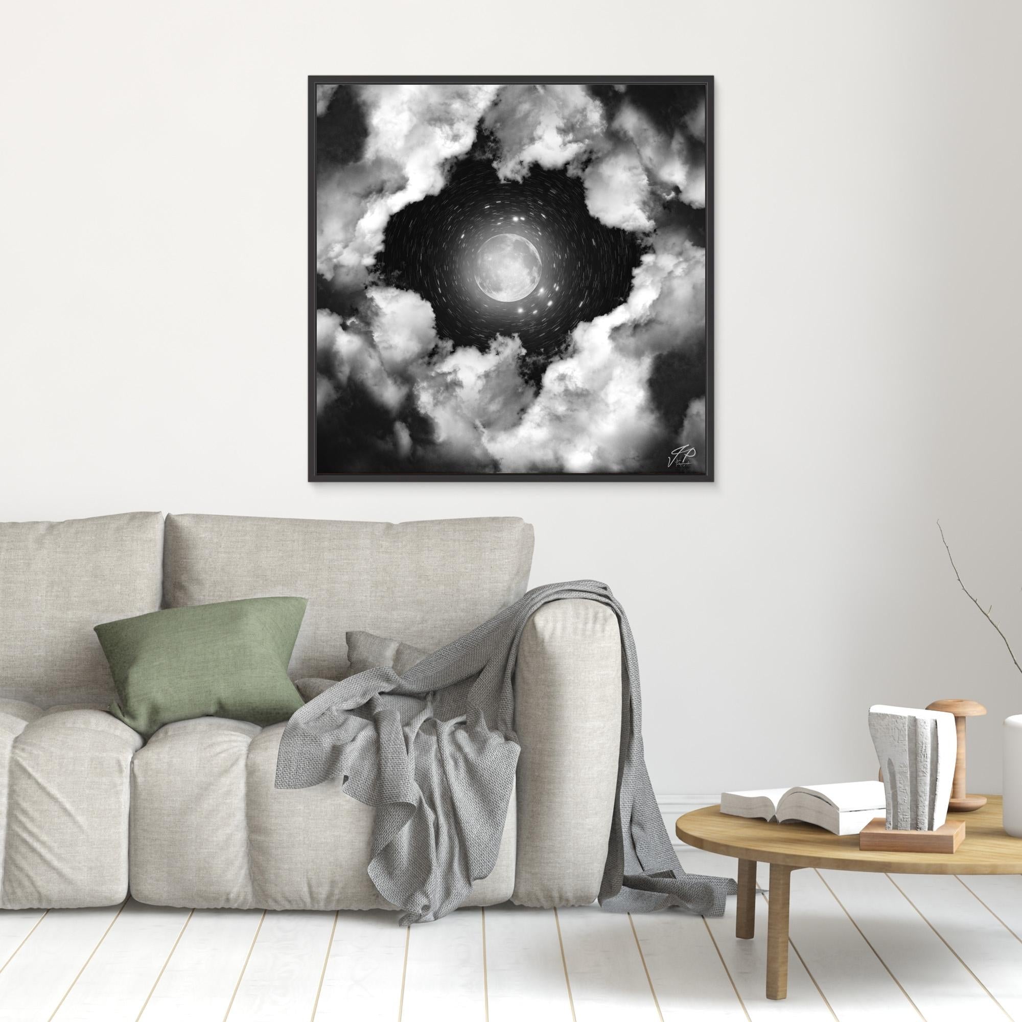 Monochrome moon and swirling clouds art above a light sofa and small round side table.