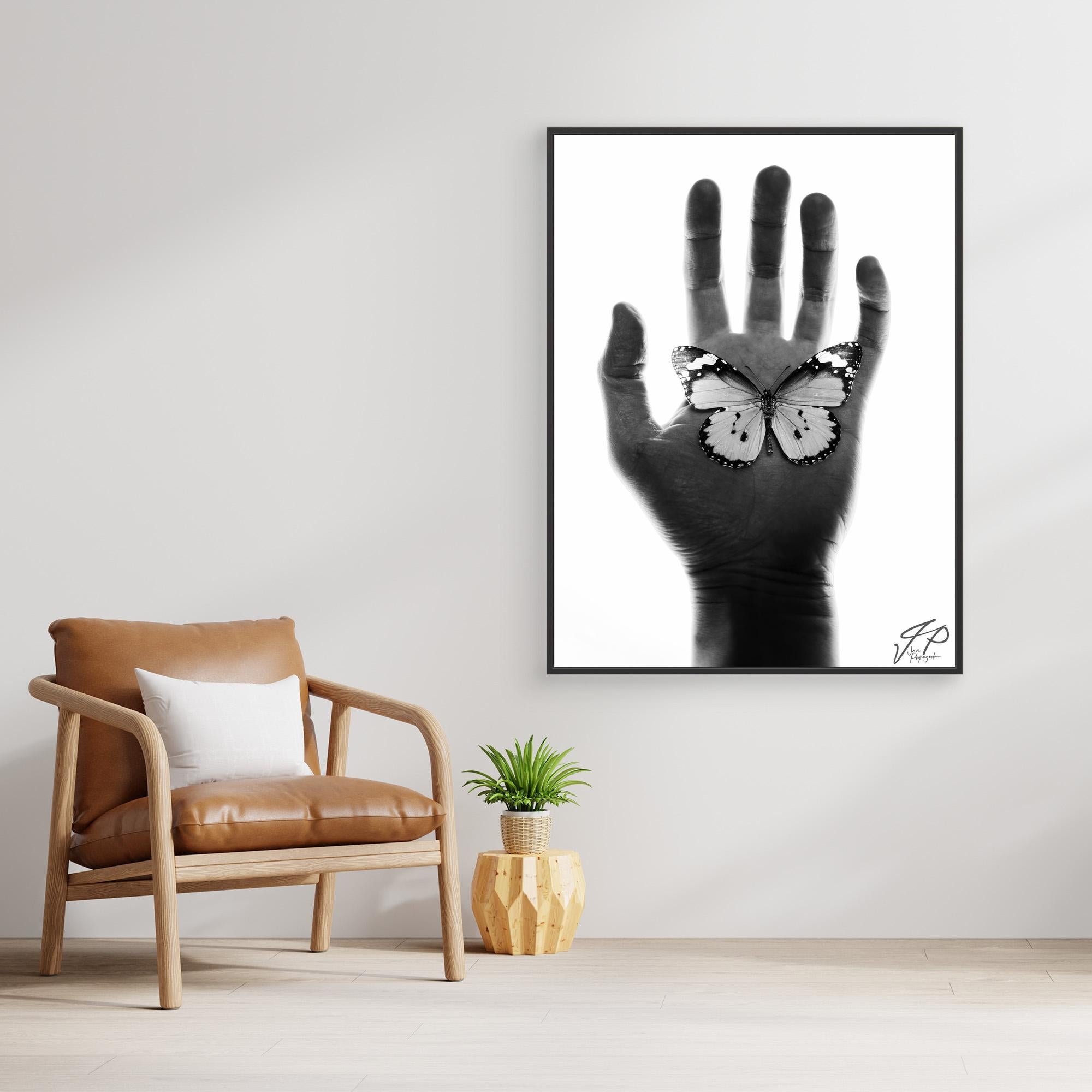 Minimalist room with tan leather chair, small plant, and black-and-white artwork of a hand with a butterfly.