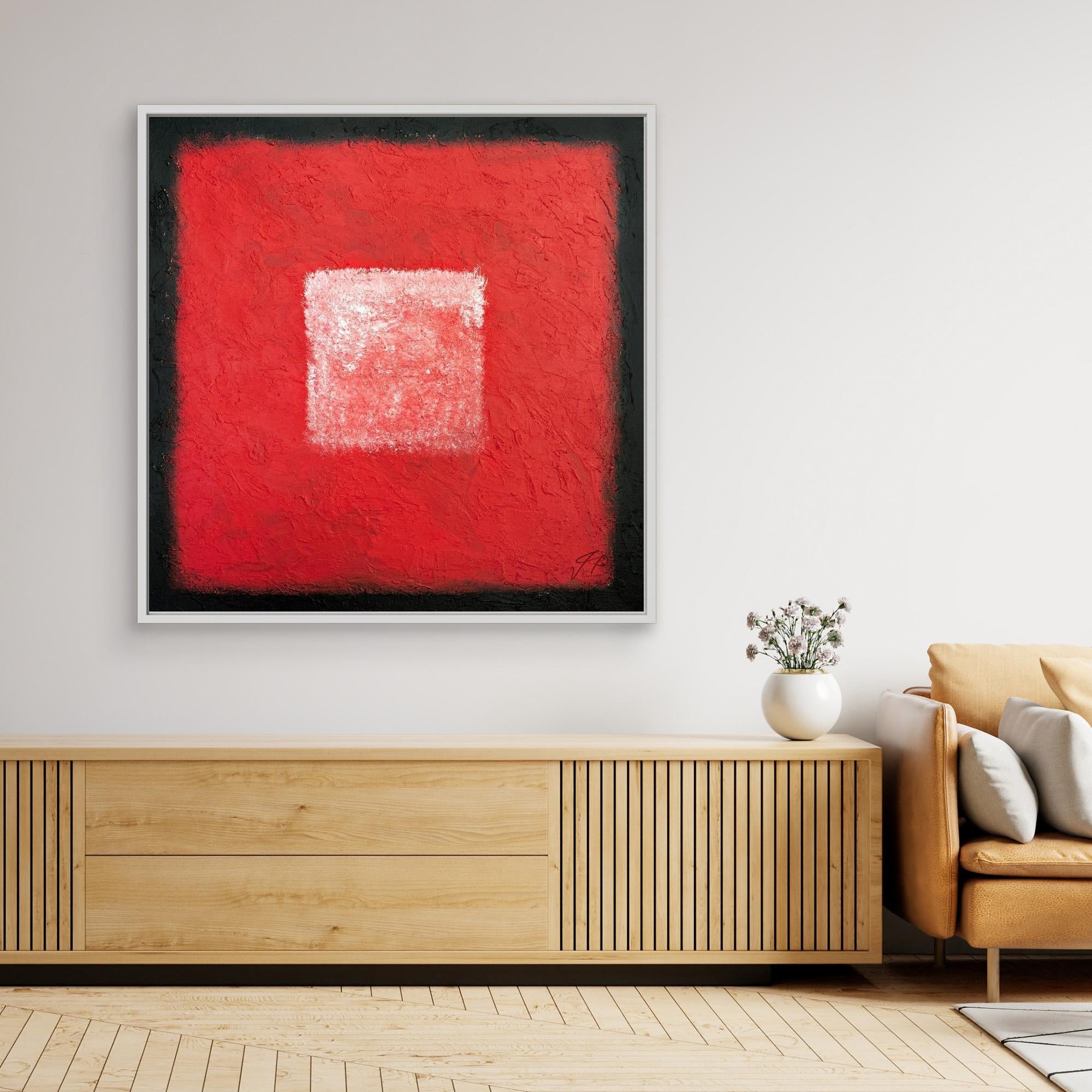 Framed red abstract artwork displayed above console table, next to tan armchair and décor vase.