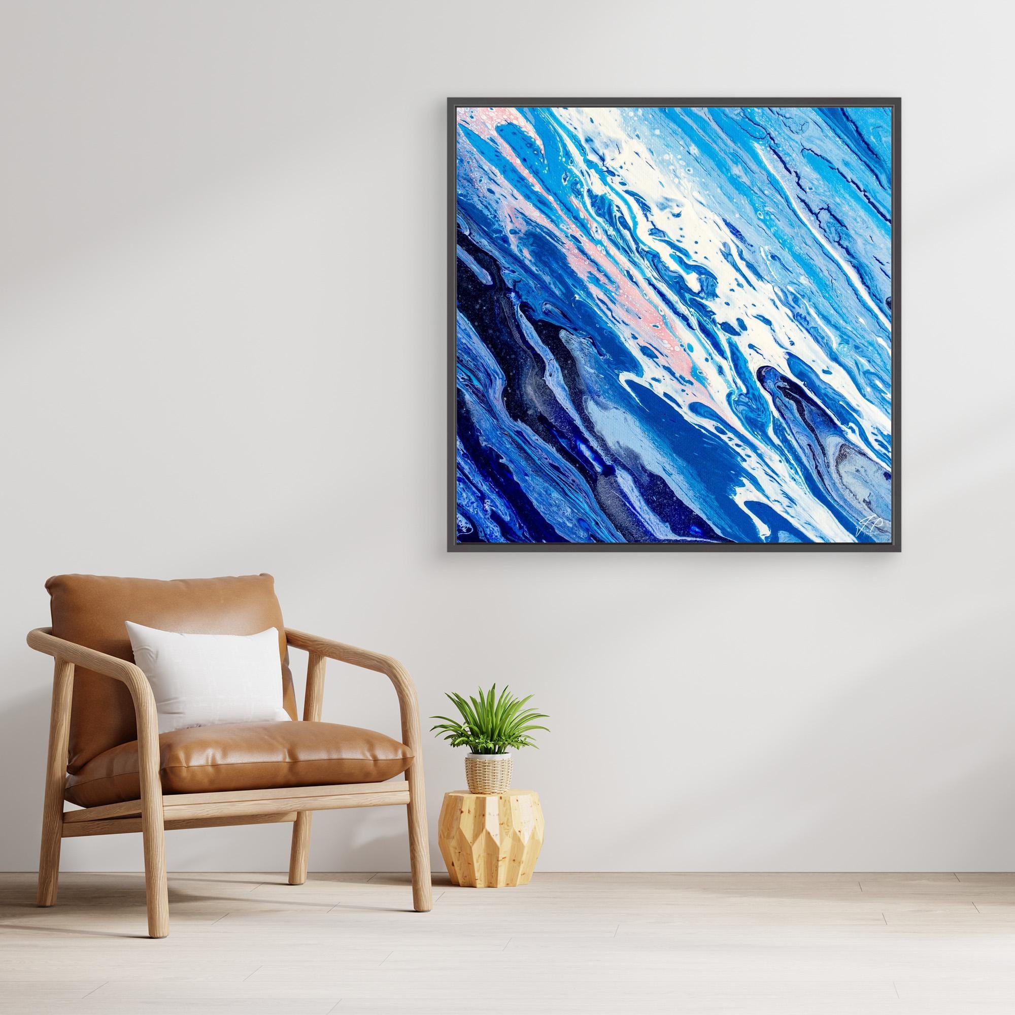 Abstract blue and white fluid art hangs above a tan chair, white pillow, and small plant in modern setting.