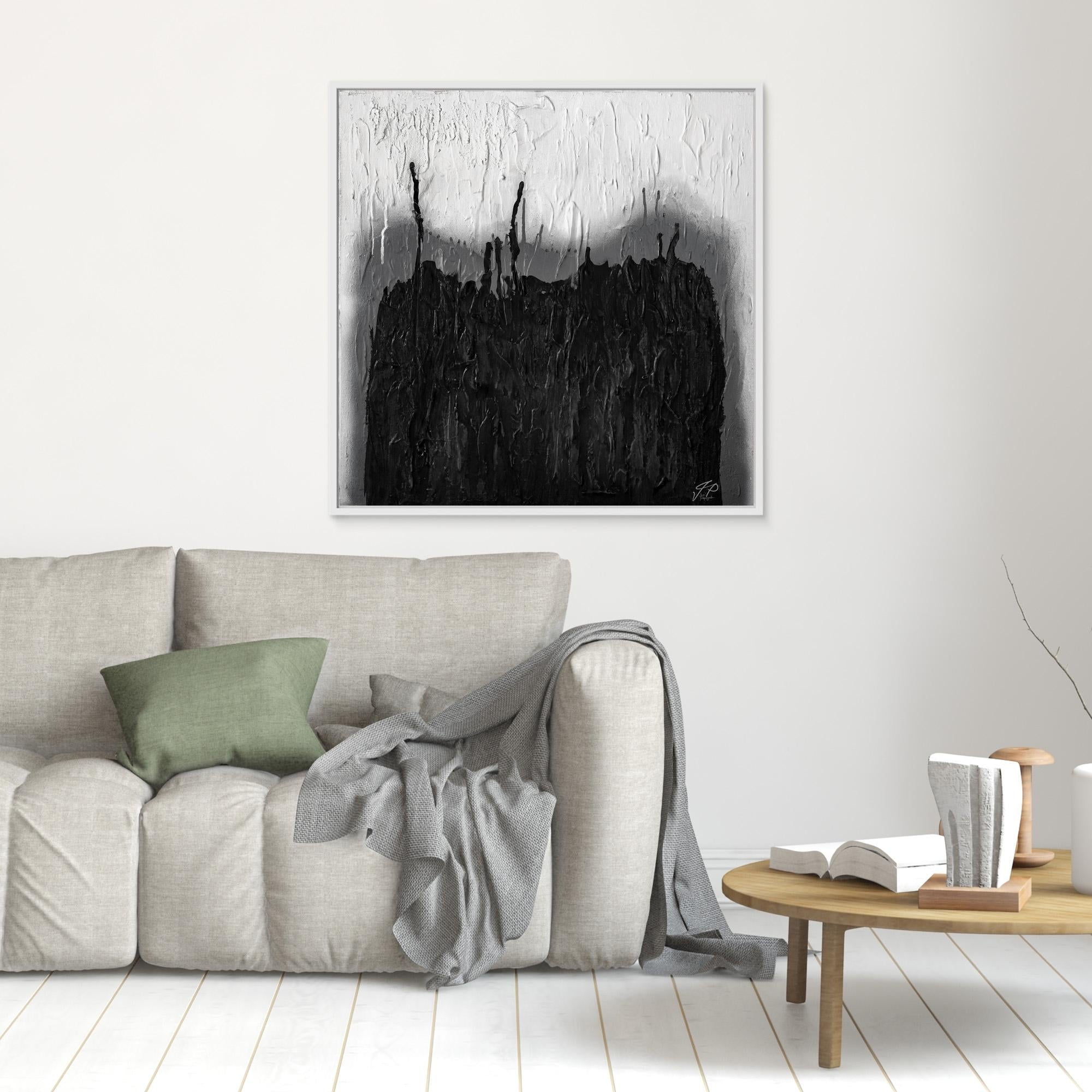 A black and white abstract painting hangs above a light gray sofa with a green pillow and gray throw blanket.
