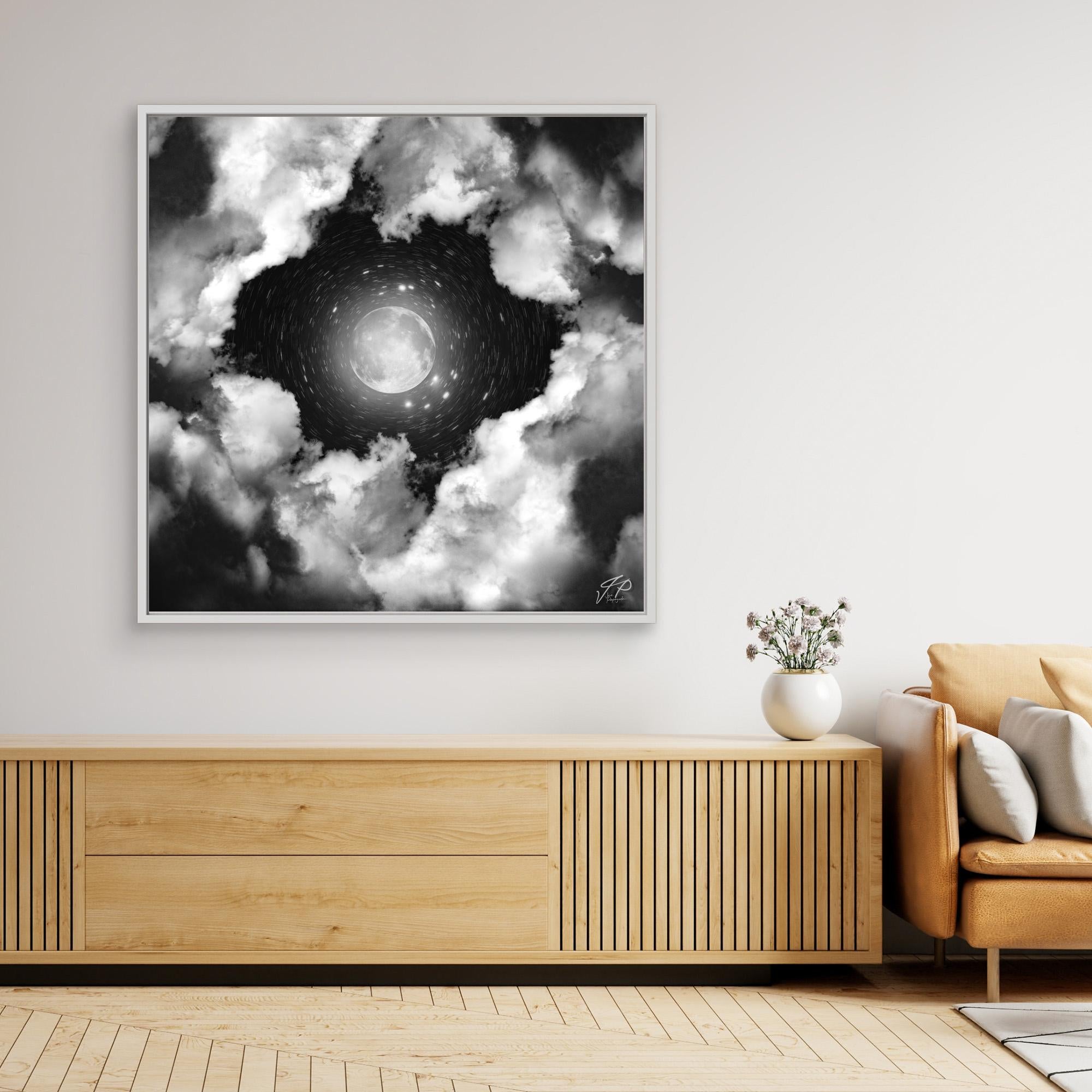 Black and white moon artwork above wooden console and tan chair in modern living room.