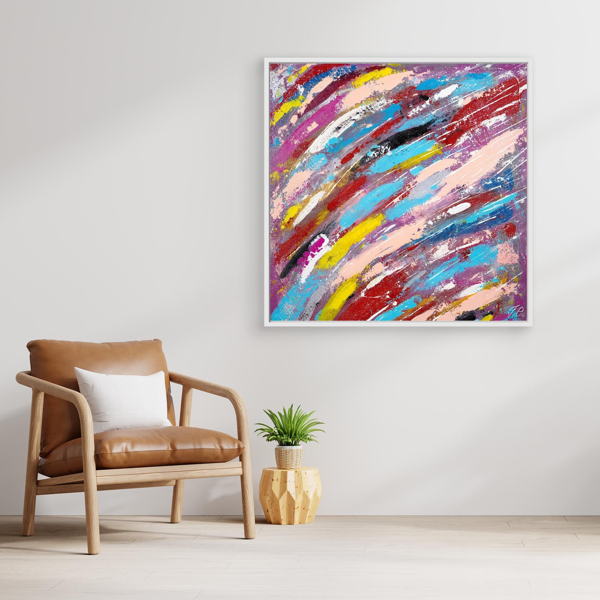 A canvas print of an abstract multicolor painting displayed on a wall above a leather chair with a white cushion, with a small potted plant to the side.