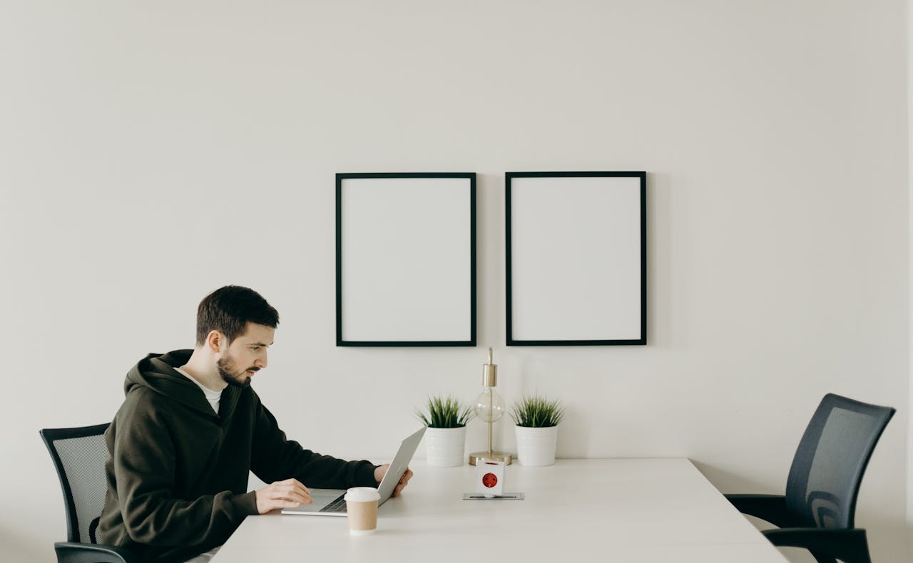 Art for the office image: Office leader in a photo of an office work room sitting at a table with wall art for business rooms.