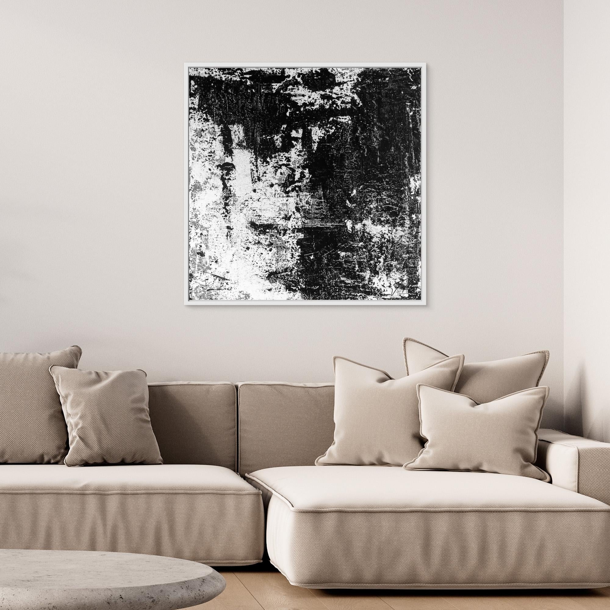 Beige sofa with decorative pillows and a black and white abstract painting on the wall.
